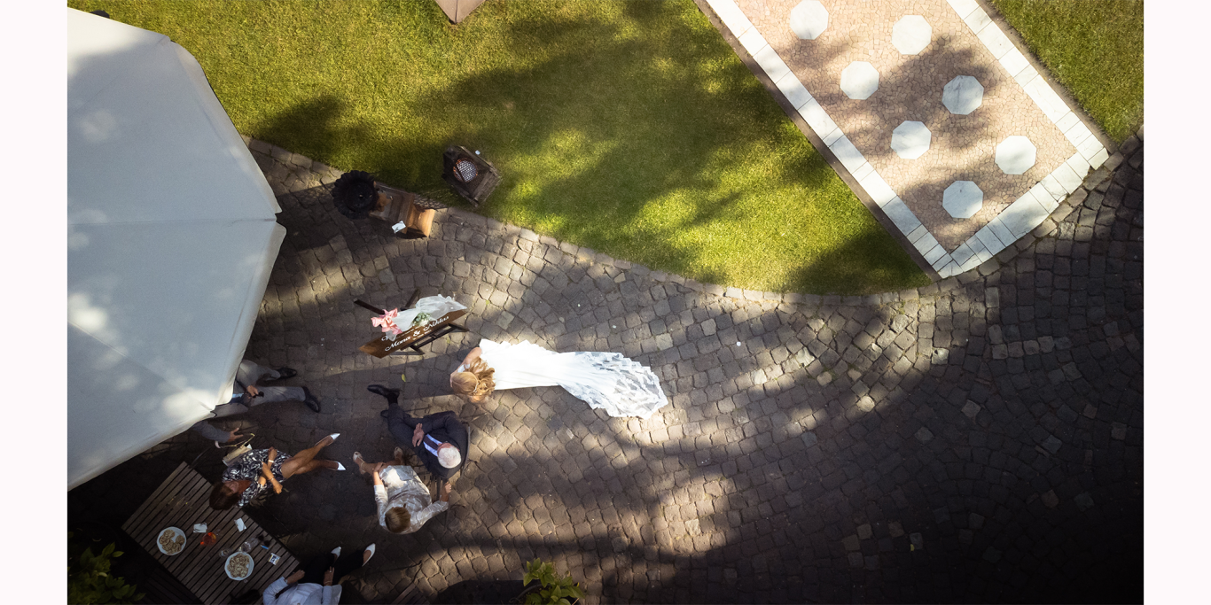 Drohne Braut Hochzeit Kommandeursburg Kerpen Hochzeitsfeier im Freien mit Gästen, einem Tisch und einer weißen Decke im Gras.
