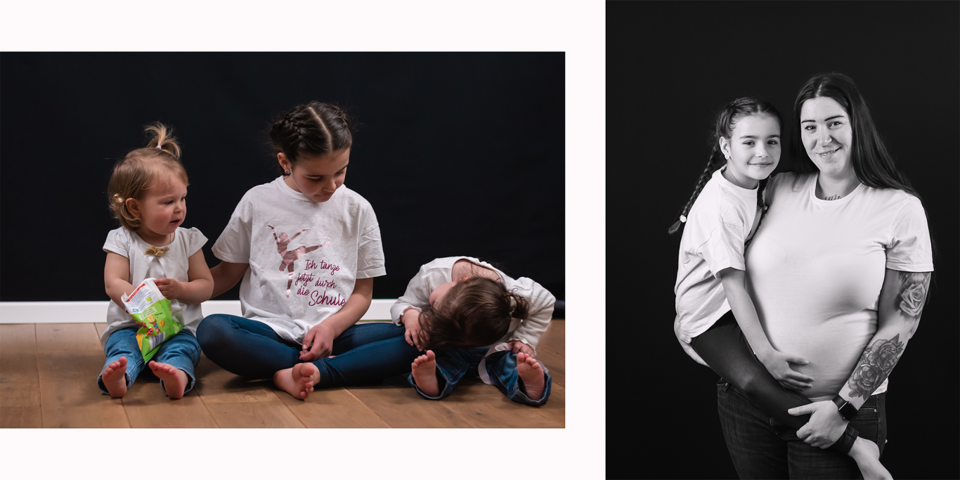 Zwei Mädchen sitzen am Boden, während eine Frau ein Kind im Arm hält.