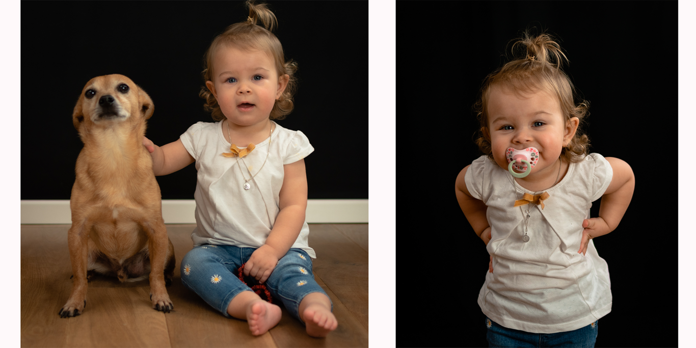 Ein kleines Mädchen sitzt neben einem Hund und posiert fröhlich mit einem Lutscher.