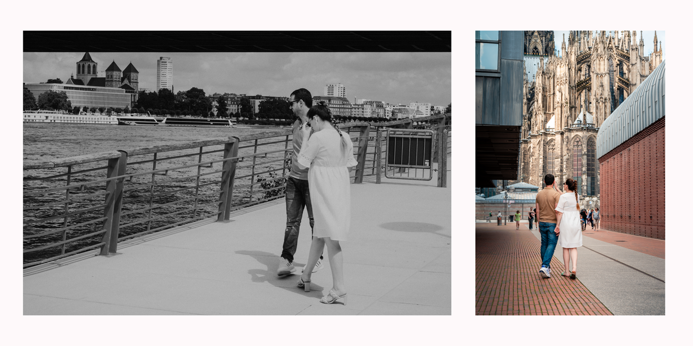 Paarshooting Köln am Rhein Paar geht Hand in Hand entlang einer Uferpromenade und erkundet eine Stadt.