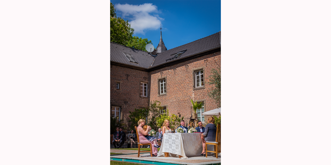 Hochzeit Trauung Kommandeursburg Kerpen-Blatzheim Familie feiert im Freien an einem Tisch neben einem Pool, umgeben von einer malerischen Kulisse.