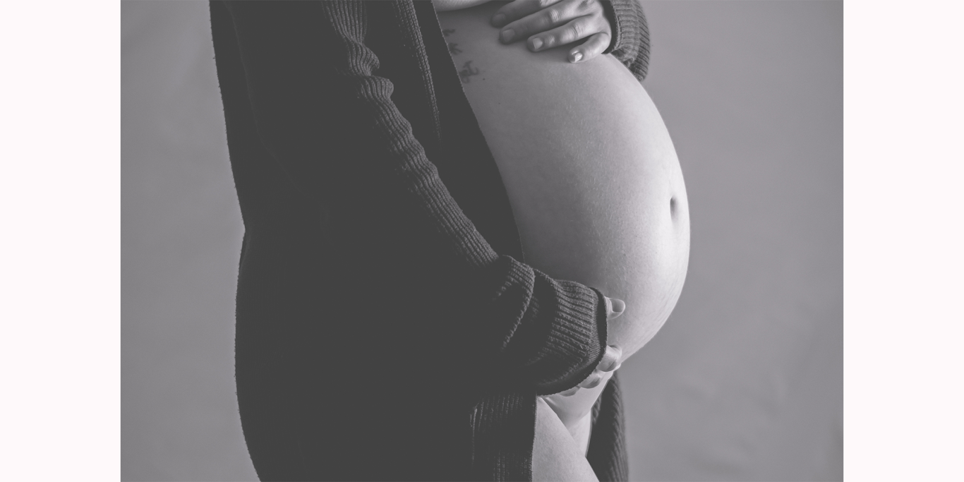Babybauchshooting in Köln Schwangere Person, die ihren Bauch sanft mit einer Hand haltet.
